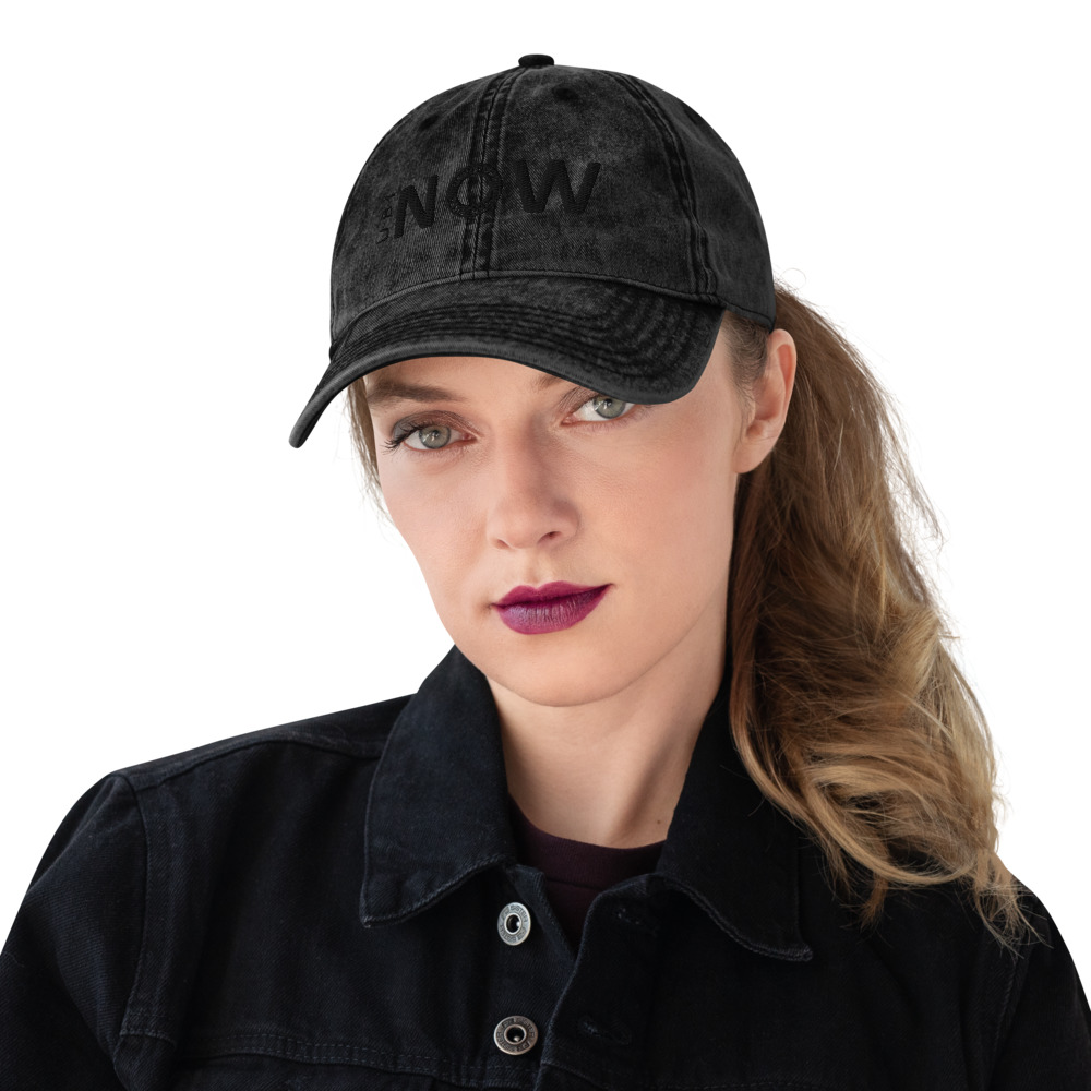Woman wearing black cap with "NOW" text.