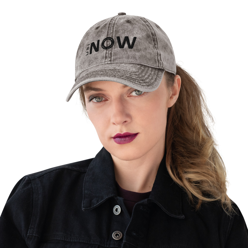 Woman wearing vintage 'NOW' cap with purple lipstick.
