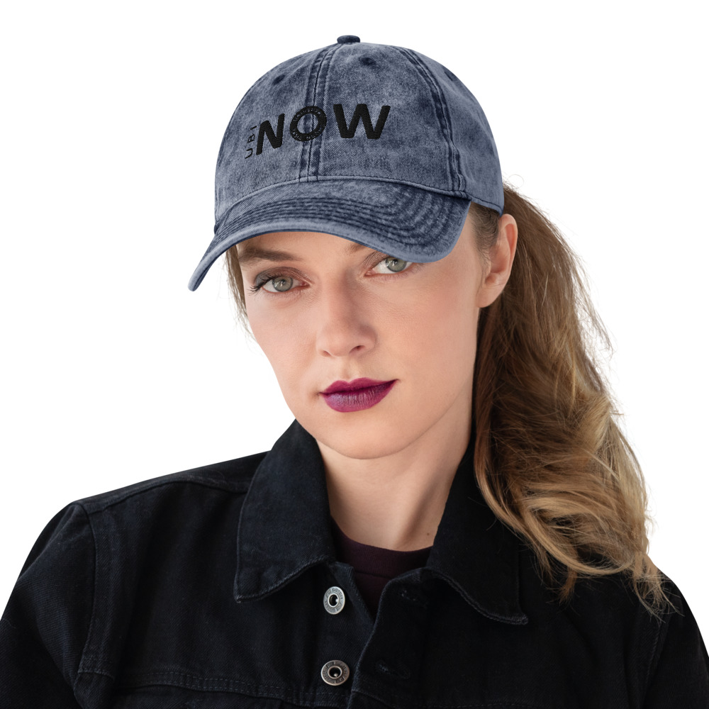 Woman wearing distressed denim cap with "NOW" logo.